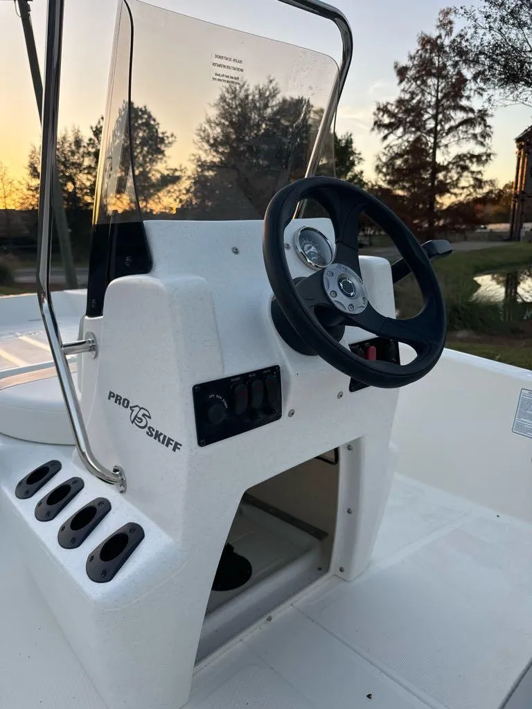 Slide: The Image of 2025 Mako Pro Skiff 15 CC boat console with steering wheel at sunset. - 7