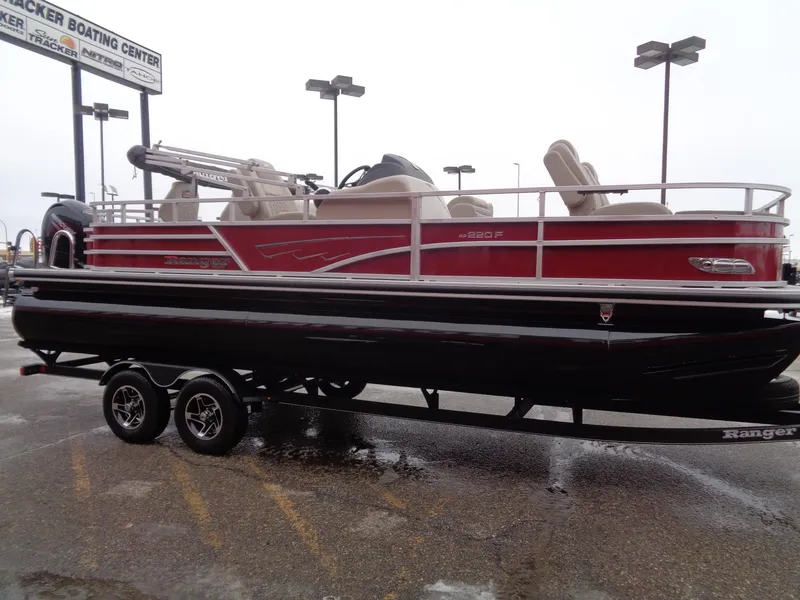 Slide: The Image of 2024 Ranger Reata 220F pontoon boat in red, parked on a trailer at a dealership. - 4