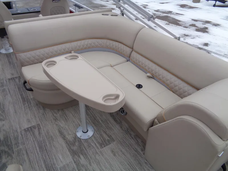 Slide: The Image of 2024 Ranger Reata 220F boat interior with beige seating and table, snowy background. - 9