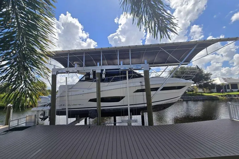 The Image of 2020 Regal 38 XO yacht on lift, dockside, under blue sky and palm trees. - 0