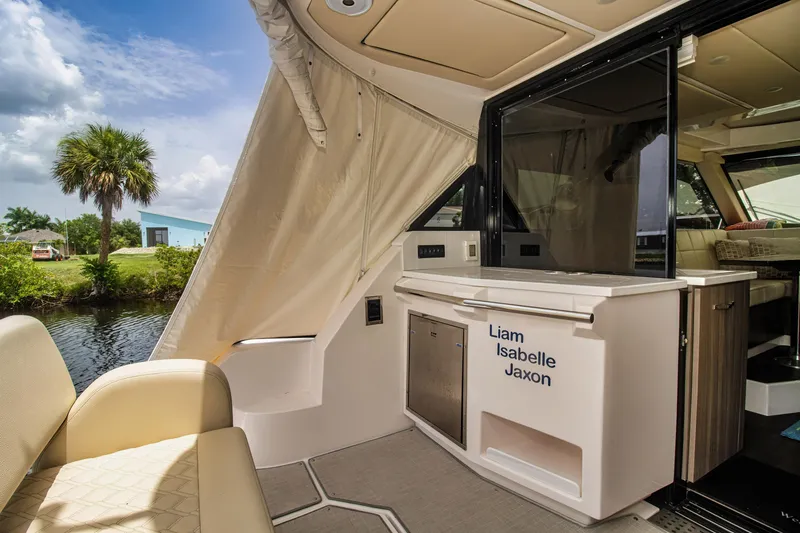 Slide: The Image of 2020 Regal 38 XO yacht interior with seating and kitchenette, near water and palm tree. - 27