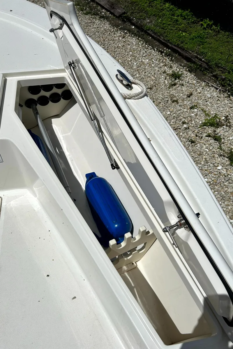 Slide: The Image of Open storage compartment on 2018 Mako 21LTS boat with blue fender and rod holders. - 12