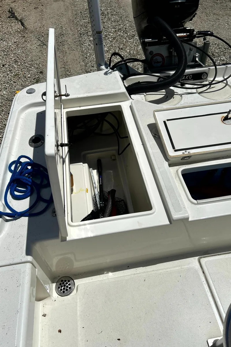 Slide: The Image of 2018 Mako 21LTS boat deck with open storage compartment and coiled rope. - 15