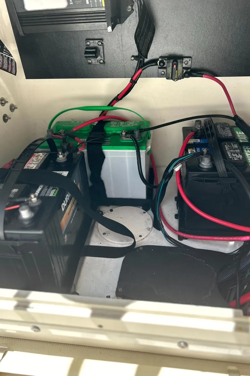 Slide: The Image of 2018 Mako 21LTS boat battery compartment with three batteries and wiring. - 18