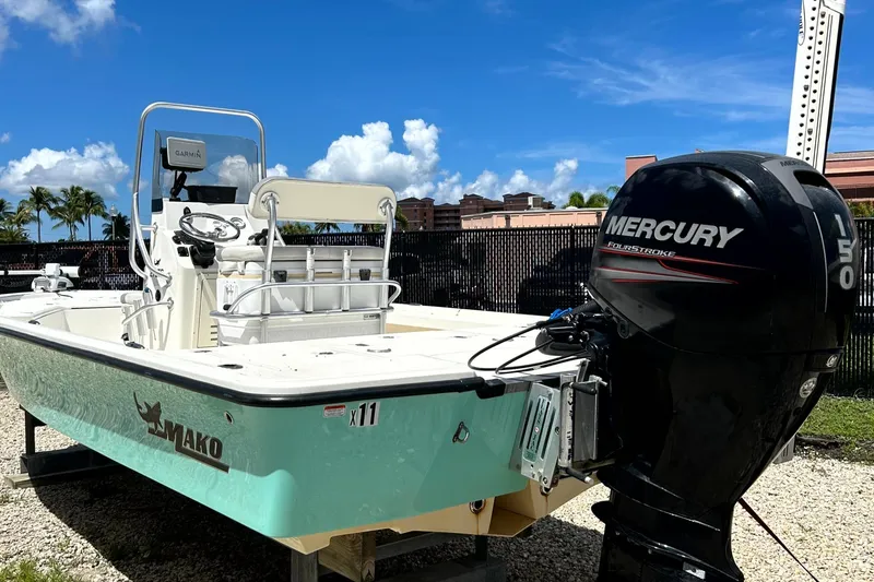 Slide: The Image of 2018 Mako 21LTS boat with Mercury engine, parked outdoors under a clear blue sky. - 2