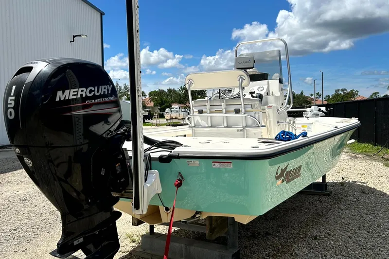 Slide: The Image of 2018 Mako 21LTS boat with Mercury outboard motor, parked outdoors under a blue sky. - 3