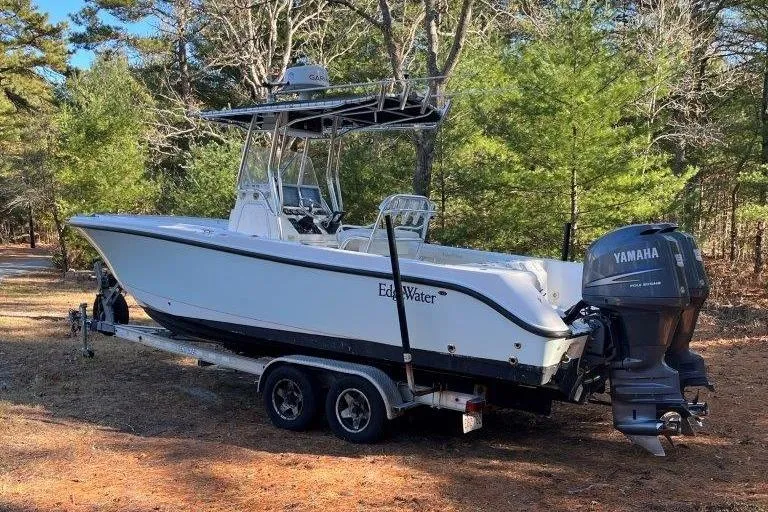 Slide: The Image of 2006 Edgewater 245CC boat on trailer with Yamaha outboard, parked in wooded area. - 3