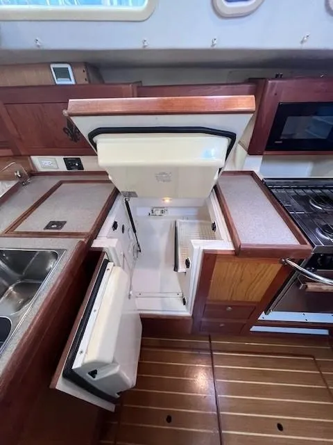 Slide: The Image of 2001 Hunter 401 yacht kitchen with open fridge, wooden cabinetry, and modern appliances. - 49