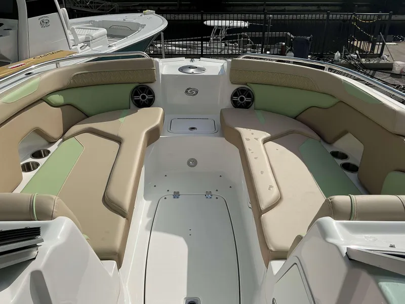 Slide: The Image of 2025 Hurricane 2400 SD boat interior with beige and green seating, cup holders, and speakers. - 13