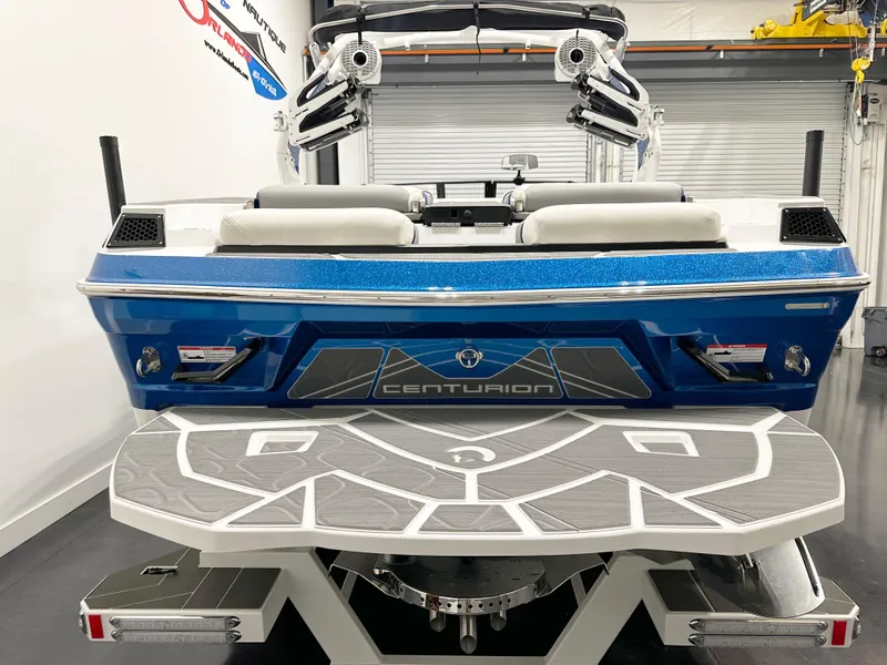 Slide: The Image of 2025 Centurion Fe23 boat, blue exterior, rear view with swim platform. - 5