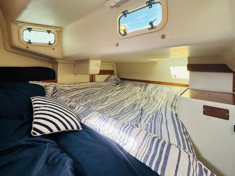 Slide: The Image of Cozy cabin interior of 1998 Catalina 320 sailboat with striped bedding and porthole windows. - 23
