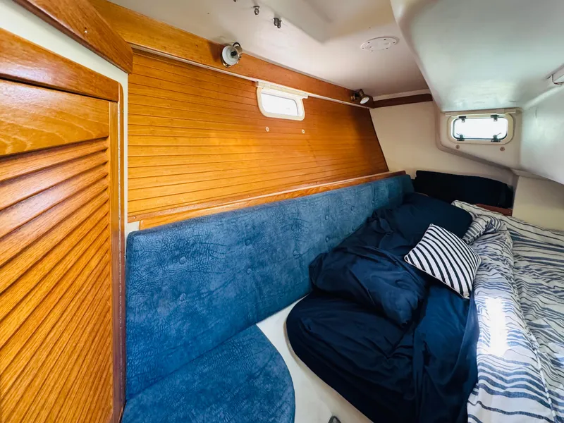 Slide: The Image of Cozy cabin interior of 1998 Catalina 320 sailboat with blue seating and striped bedding. - 24