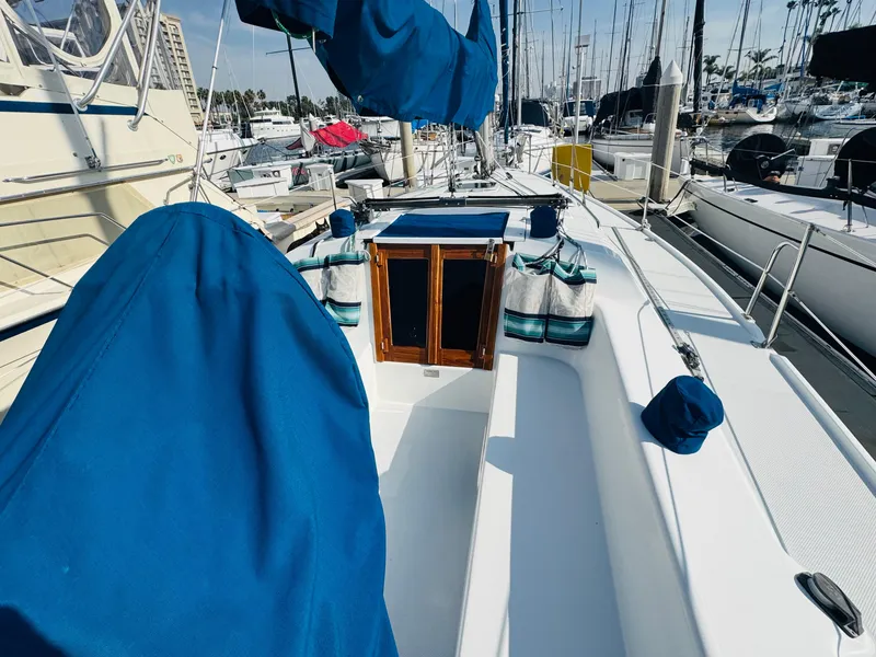 Slide: The Image of 1998 Catalina 320 sailboat docked in marina, featuring blue covers and wooden hatch. - 7