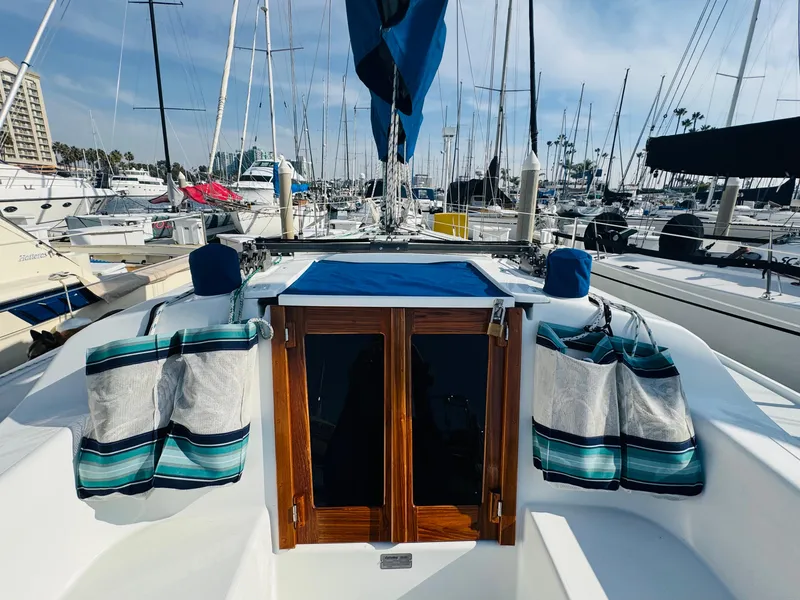 Slide: The Image of 1998 Catalina 320 sailboat in marina, featuring wooden doors and striped cushions. - 9