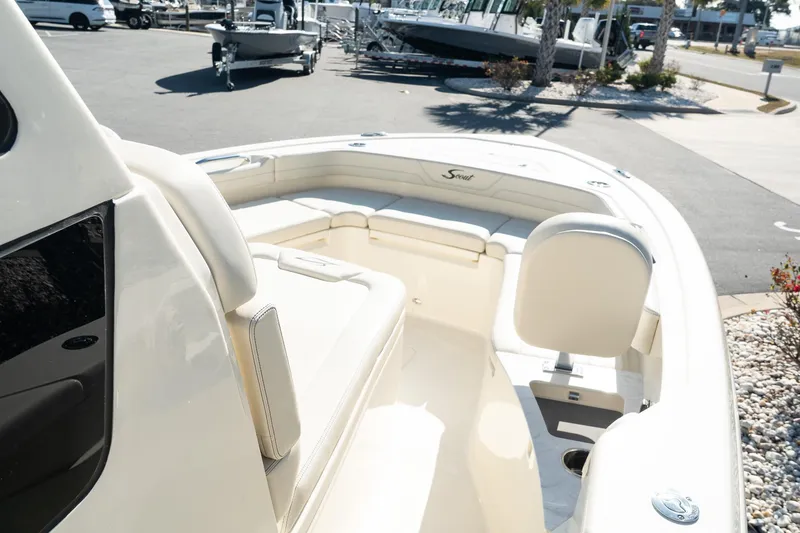 Slide: The Image of 2025 Scout 261 XSS boat interior with seating and console in a marina setting. - 19