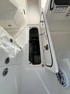 Slide: The Image of 2021 Pursuit DC 266 Dual Console boat storage compartment open, showcasing interior space. - 21