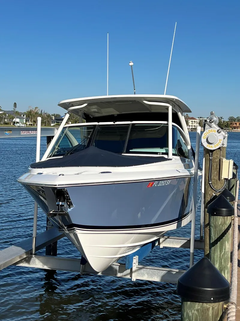 Slide: The Image of 2021 Pursuit DC 266 Dual Console boat docked on a lift in a marina. - 33