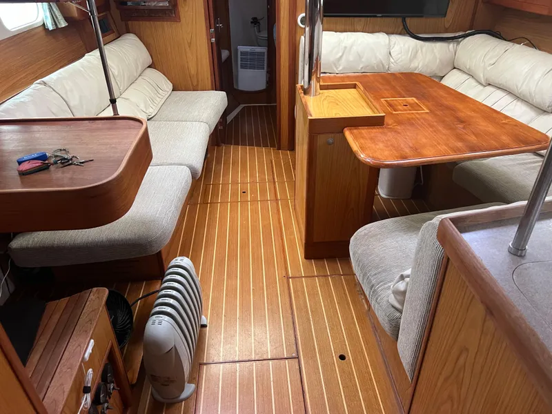 Slide: The Image of Interior of a 2000 Hunter 410 sailboat with wooden flooring and cushioned seating. - 15
