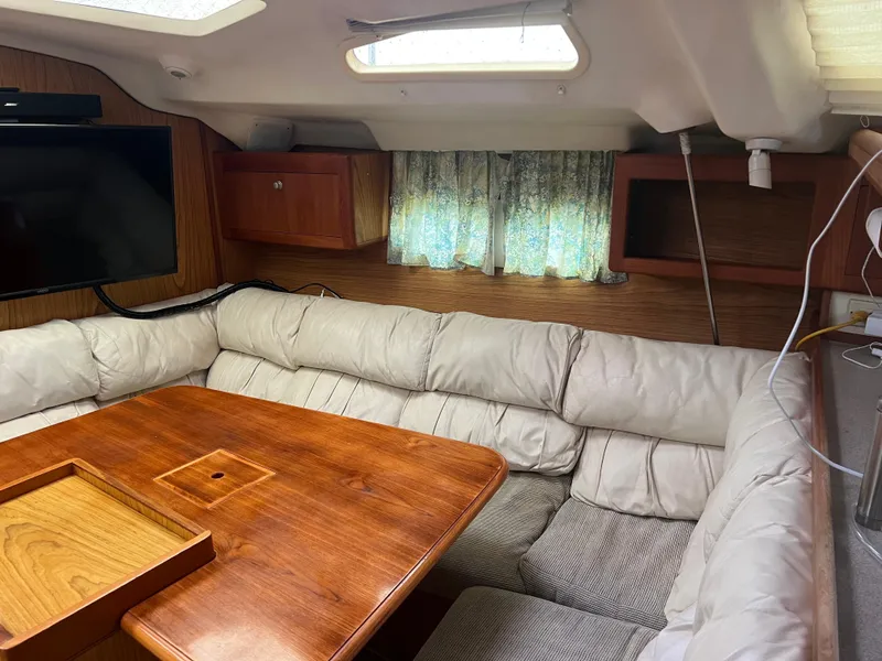 Slide: The Image of Cozy interior of 2000 Hunter 410 sailboat with cushioned seating and wooden table. - 16