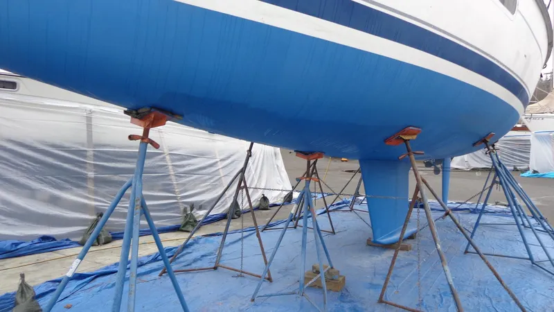 Slide: The Image of Hunter 410 sailboat named "Helluva" on stands, 2000 model, in a boatyard. - 6