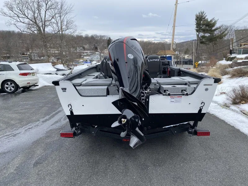 Slide: The Image of 2025 Lund 1775 Impact XS SS boat, rear view, parked on snowy road. - 2