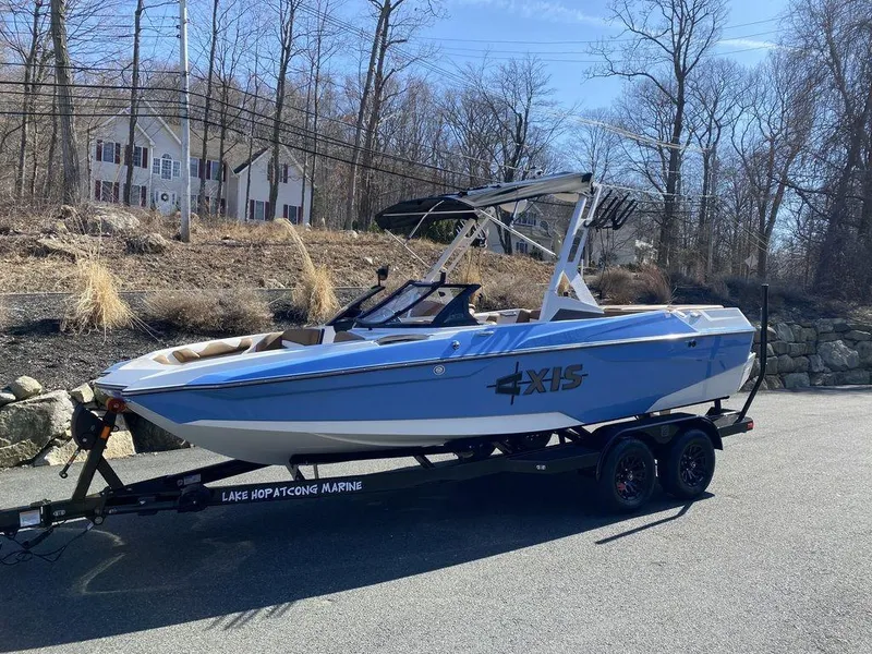 Slide: The Image of 2025 Axis A20 boat on trailer, parked outdoors, with trees and houses in the background. - 1