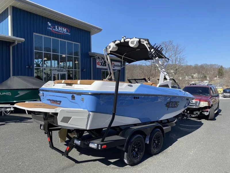 Slide: The Image of 2025 Axis A20 boat on trailer outside dealership, blue exterior, sunny day. - 3