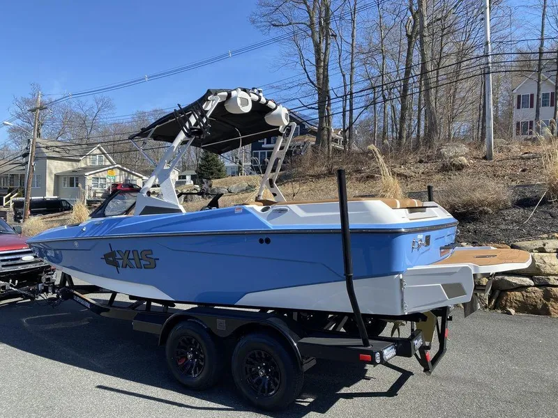 Slide: The Image of 2025 Axis A20 boat on trailer, blue and white design, parked outdoors. - 4