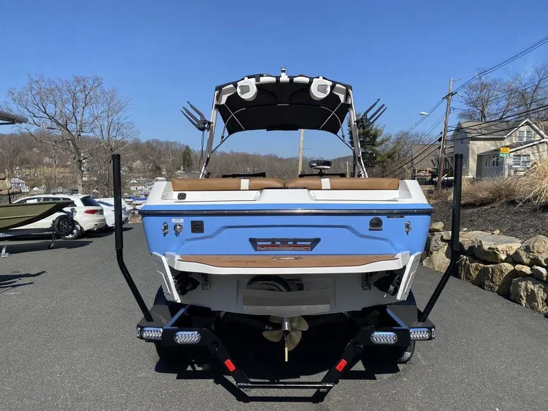 Slide: The Image of 2025 Axis A20 boat, blue exterior, parked on a trailer in a sunny outdoor setting. - 5