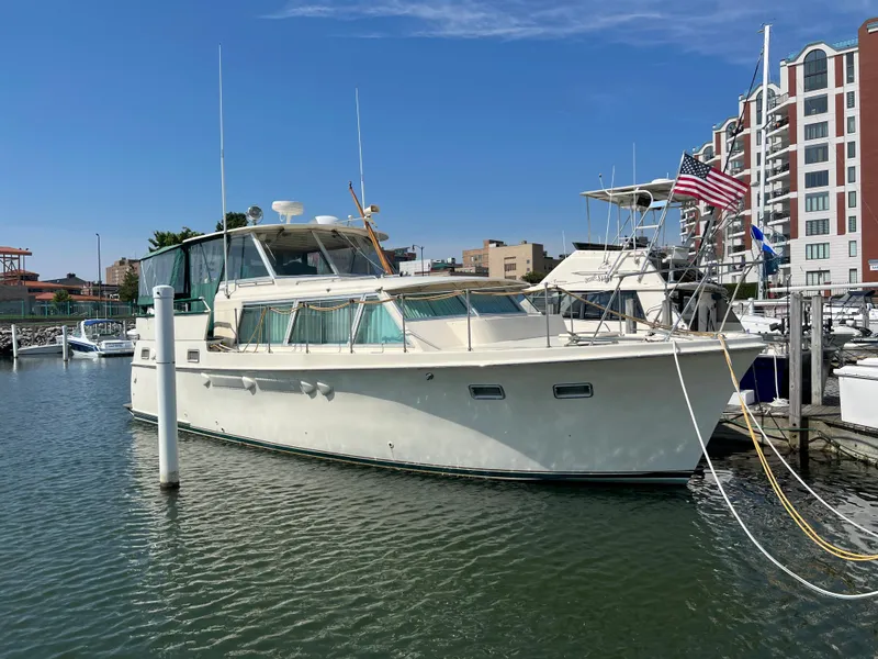 Slide: The Image of 1967 Hatteras 41 Twin Cabin yacht docked in marina, clear sky, urban backdrop. - 3