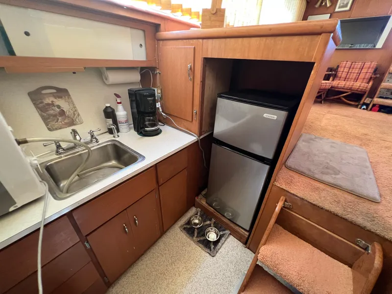 Slide: The Image of 1967 Hatteras 41 Twin Cabin kitchen with sink, fridge, and wooden cabinetry. - 38