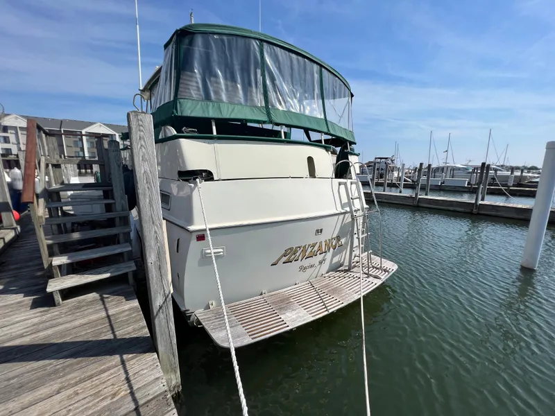 Slide: The Image of 1967 Hatteras 41 Twin Cabin docked at marina, featuring green canopy and wooden deck. - 7