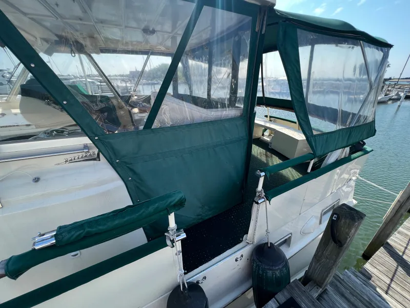 Slide: The Image of 1967 Hatteras 41 Twin Cabin with green canopy docked at marina. - 9