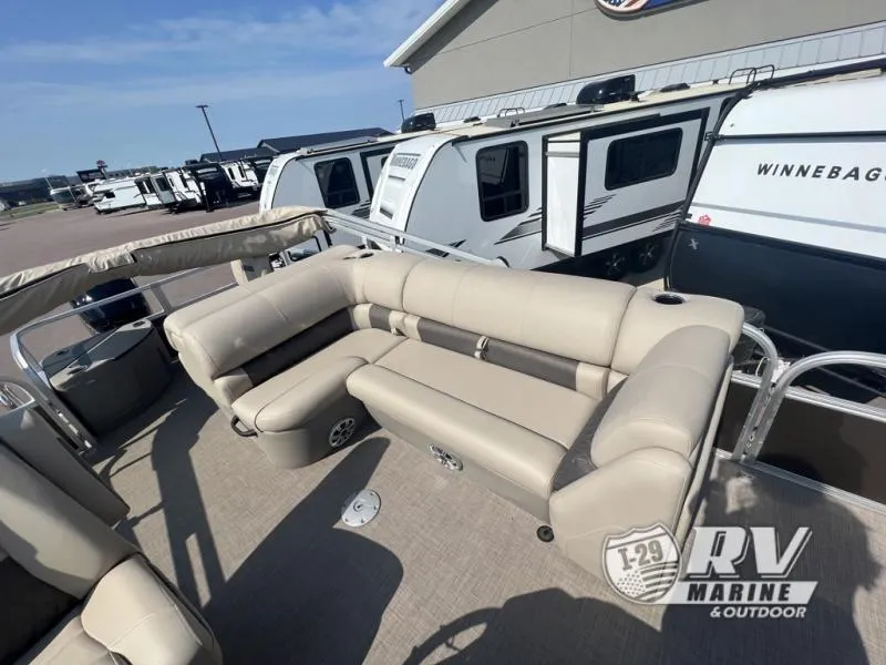 Slide: The Image of 2023 Sportfish 20 DLX pontoon boat with beige seating, parked near RVs. - 13