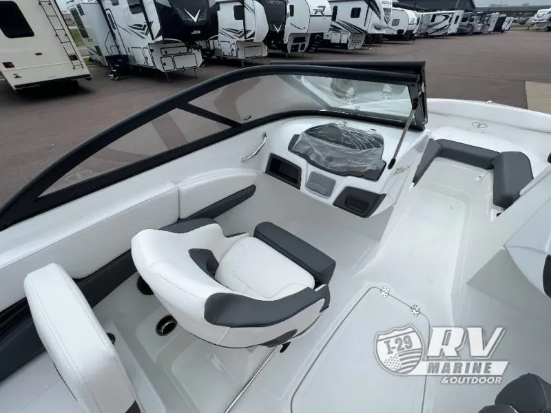 Slide: The Image of 2024 Tahoe 210S boat interior with white seating and dashboard, parked near RVs. - 6