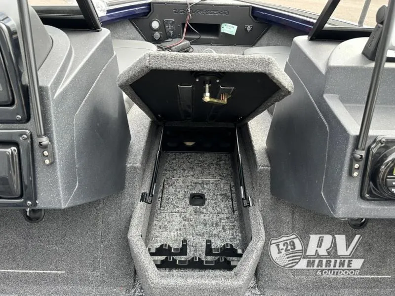 Slide: The Image of 2025 Targa 18 boat interior with open storage compartment, gray carpet, and dashboard controls. - 9