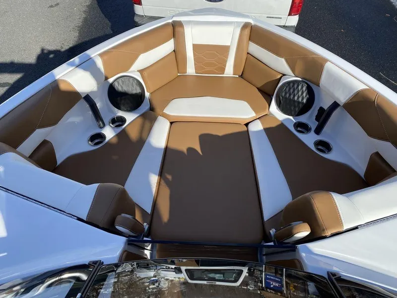 Slide: The Image of 2025 Malibu 23 LSV boat interior with brown and white seating, cup holders, and speakers. - 16