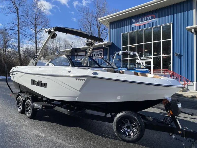Slide: The Image of 2025 Malibu 23 LSV boat on trailer outside dealership, sunny day. - 3