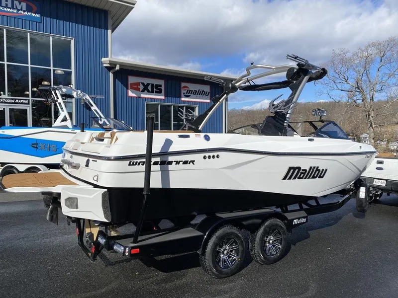 Slide: The Image of 2025 Malibu 23 LSV boat on trailer, parked outside dealership under blue sky. - 4