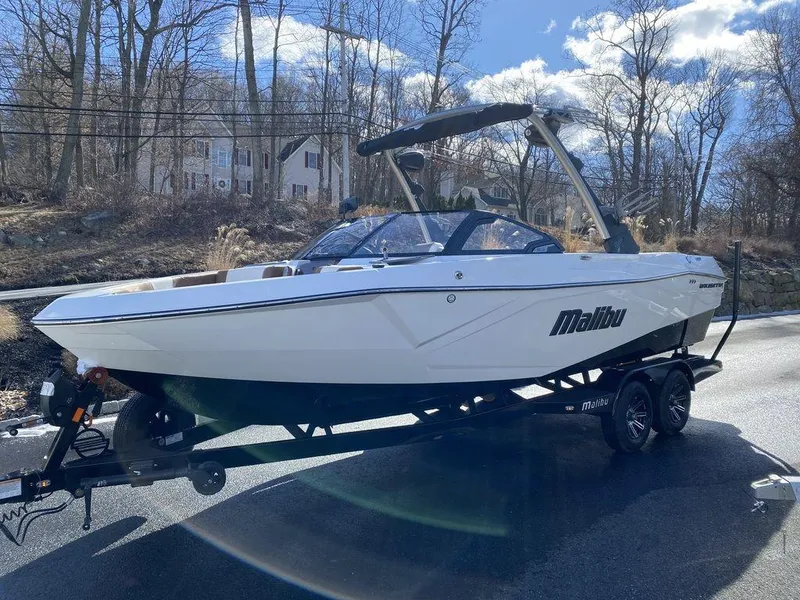 Slide: The Image of 2025 Malibu 23 LSV boat on trailer, parked on a sunny road. - 7