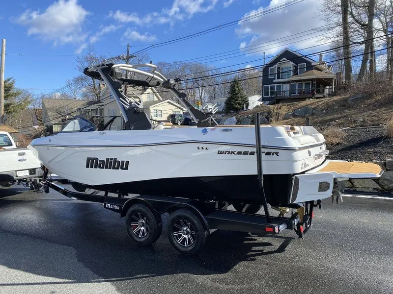 Slide: The Image of 2025 Malibu 23 LSV boat on trailer, parked outdoors on a sunny day. - 8