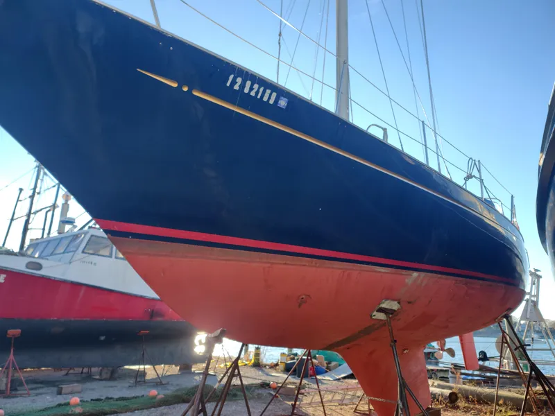 Slide: The Image of 1984 Belliure Sloop sailboat on stands, blue hull with red stripe, dockside view. - 3