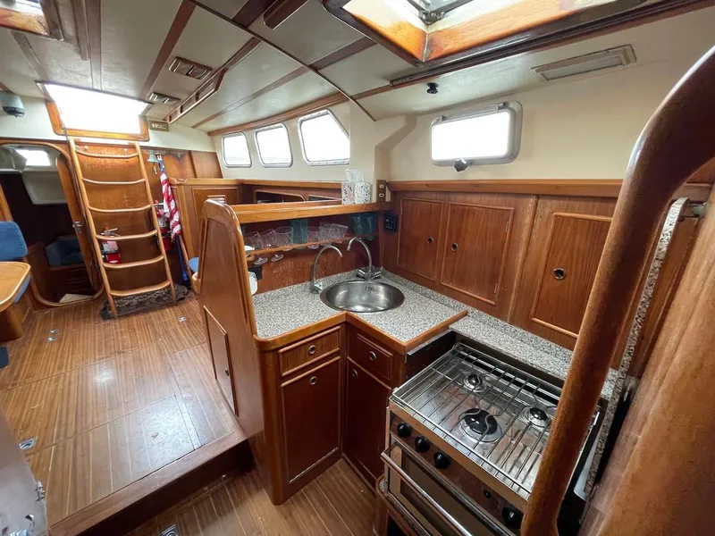 Slide: The Image of 1984 Belliure Sloop interior with wooden cabinetry, compact kitchen, and nautical design elements. - 5