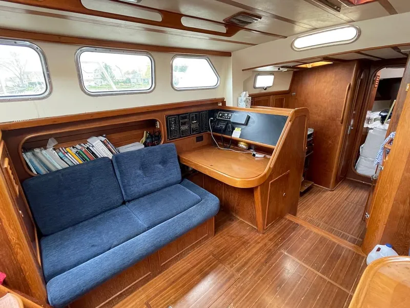 Slide: The Image of 1984 Belliure Sloop interior with wooden finish, blue sofa, and navigation station. - 6