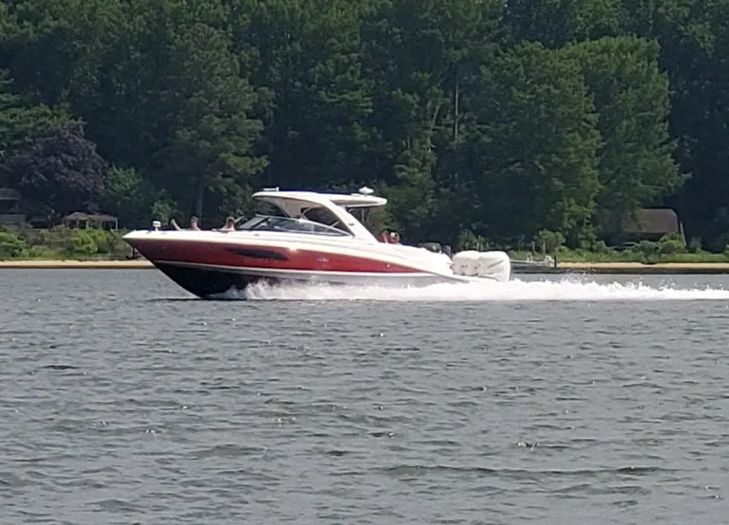 Slide: The Image of 2017 Sea Ray 350 SLX cruising on a lake with lush green trees in the background. - 2