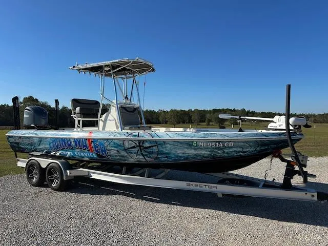 Slide: The Image of 2023 Skeeter SX241 boat on trailer, parked outdoors under clear blue sky. - 3