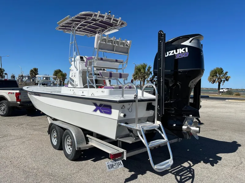 Slide: The Image of 2018 Shallow Sport 25 X3 boat on trailer with Suzuki engine, parked outdoors. - 1