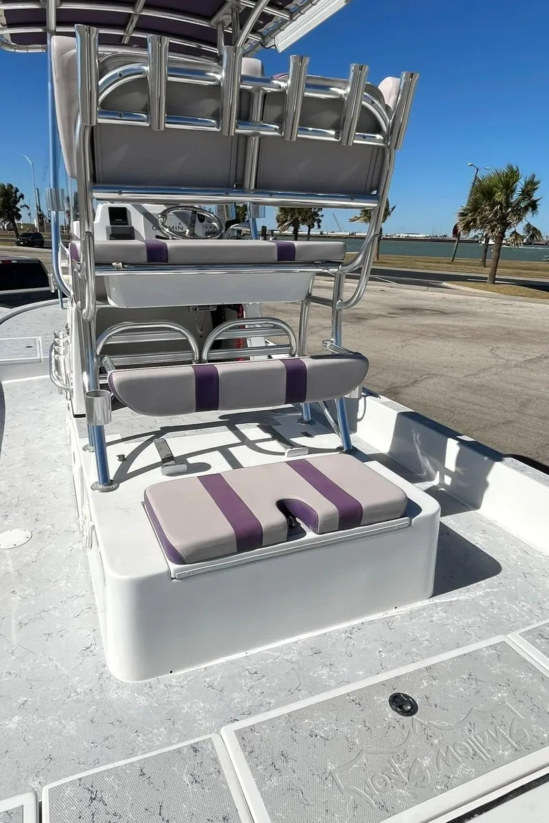 Slide: The Image of 2018 Shallow Sport 25 X3 boat with cushioned seating and rod holders, docked under clear skies. - 14