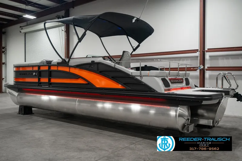Slide: The Image of 2025 Bennington 23 RSB pontoon boat in showroom, featuring sleek orange and black design. - 6