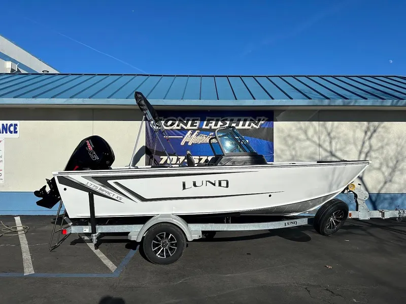 Slide: The Image of 2025 Lund 1775 Impact XS Sport boat on trailer, parked outdoors. - 0